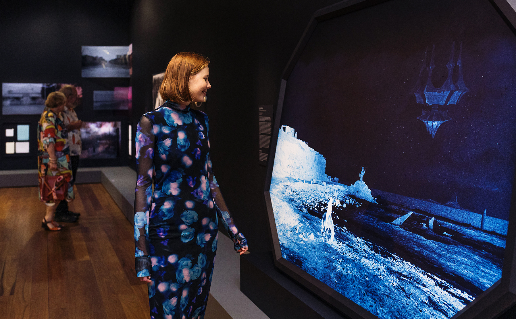 A girl smiling at a futuristic looking artwork.